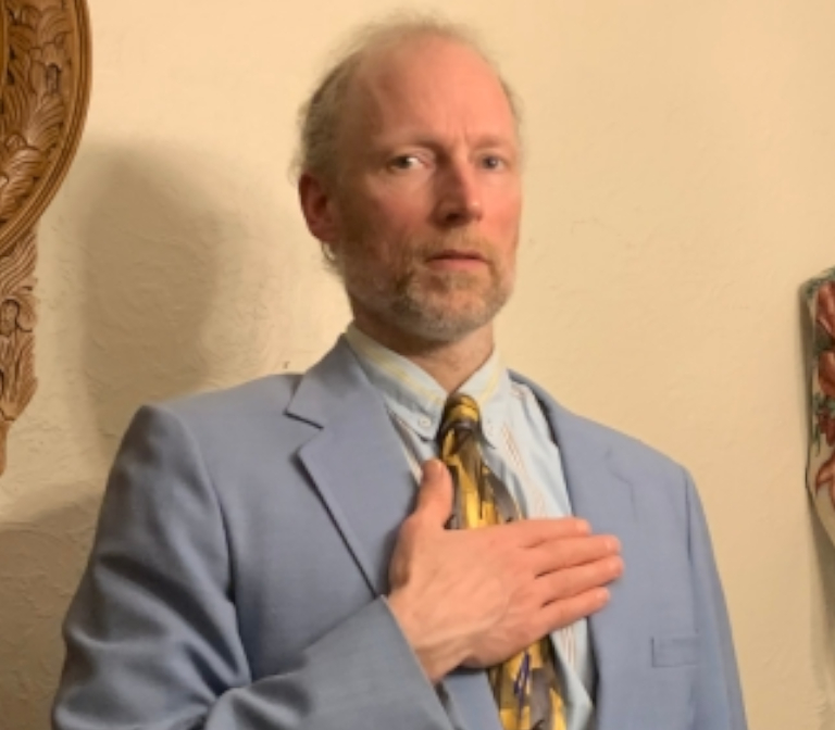 Matt Mandell hand on heart in his suit